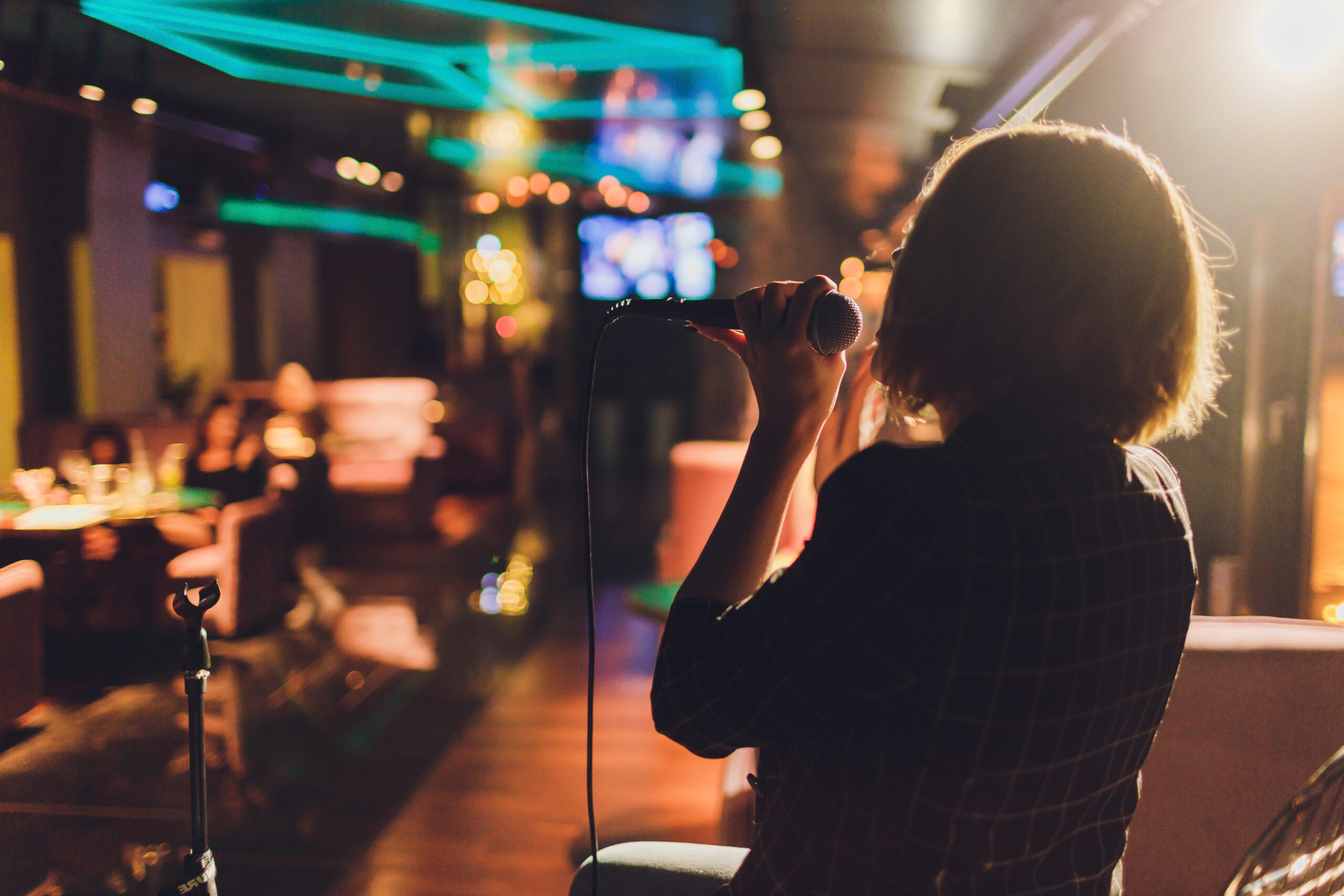 Young woman singing in karaoke and holding a microphone close-up. Singer at a party or concert on the background of a luminous star and smoke.